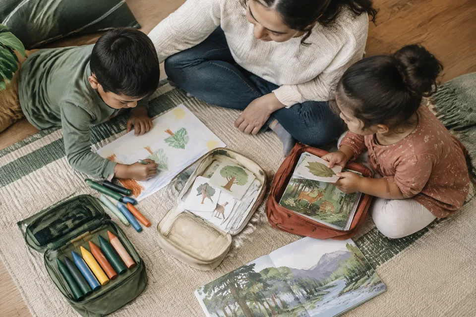 Clear overhead view of three age-appropriate travel pouches with large drawing tools, picture cards and picture-only books.